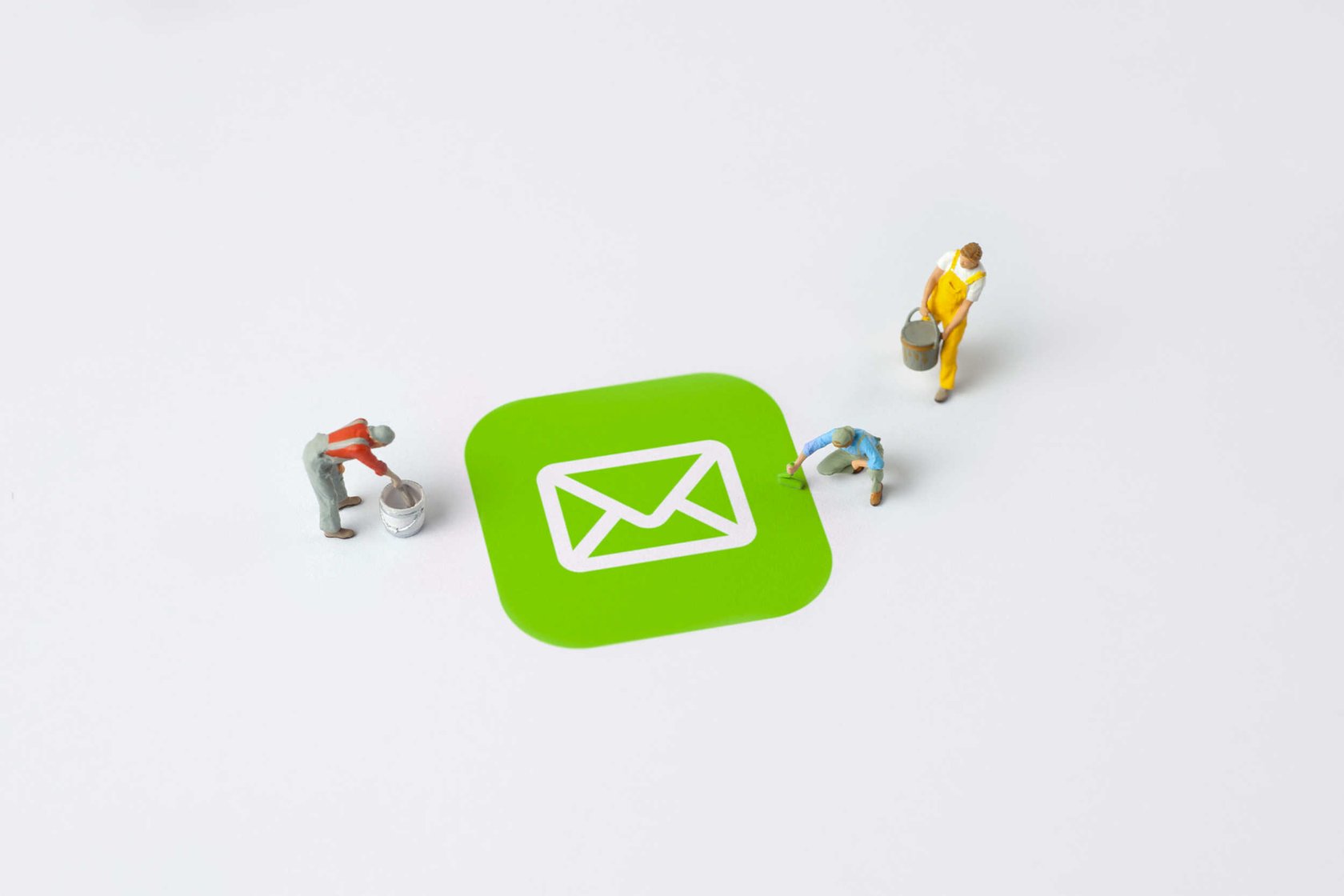 Three workers stand around and paint a green email icon drawn on the floor